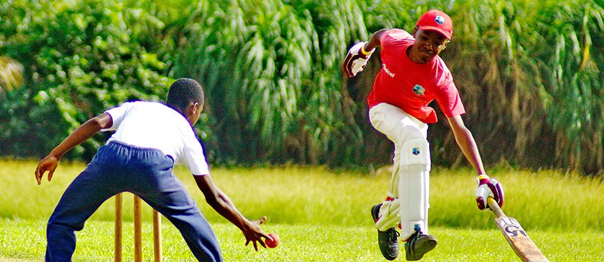 Two young, aspiring cricketers hone their skills on a grassy turf